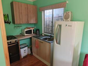 a small kitchen with a refrigerator and a sink at Cabaña YEYITA Playa Las Ventanas in Puchuncaví