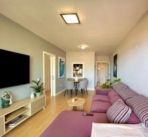 a living room with a purple couch and a flat screen tv at MAR AZUL Playa y Piscina 80 metros de la playa in Roquetas de Mar