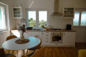 a kitchen with a table and a table and chairs at Seaside house for families with children Cove Nevidjansko Polje, Pasman - 24036 in Neviđane