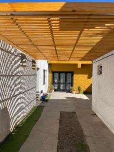 a yellow building with a wooden roof over a driveway at Casa pura vida in General Roca