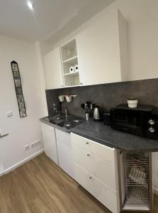 メンヒェングラートバッハにあるStilvolles Studio Apartment im Zentrum MGの白いキャビネットと黒いカウンタートップを備えたキッチン