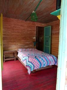 a bedroom with a bed in a wooden room at Hotel y Estadero Los Colores in Pajarito