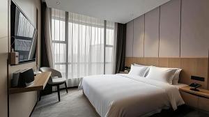 a hotel room with a large bed and a desk at Paco Hotel Guangzhou Baiyun Airport Liantang Metro in Huadu