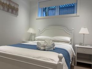 a bedroom with a white bed with towels on it at Fancy Family Suite with Parking near UBC in Vancouver