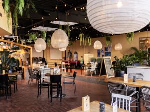 een restaurant met tafels, stoelen en verlichting bij Holiday Home Brouwersdam with Sauna in Brouwershaven