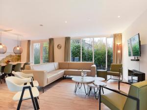 een woonkamer met een bank en tafels en stoelen bij Holiday Home Brouwersdam with Sauna in Brouwershaven