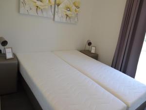 a white bed in a room with flowers on the wall at Holiday Home in Bemelen near Nature Reserve in Bemelen +31 photos