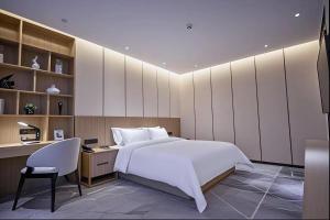 a bedroom with a bed and a desk and a chair at Paco Hotel Guangzhou Baiyun Airport Liantang Metro in Huadu