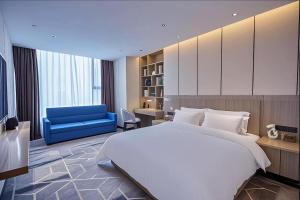 a bedroom with a large white bed and a blue couch at Paco Hotel Guangzhou Baiyun Airport Liantang Metro in Huadu