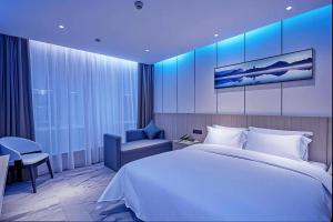 a hotel room with a large bed and a chair at Paco Hotel Guangzhou Baiyun Airport Liantang Metro in Huadu
