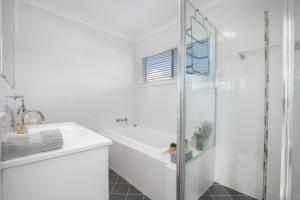 a white bathroom with a tub and a sink at Location at Harrington in Harrington +11 photos