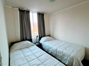 two beds in a room with a window at Vista Bahía Puerto Valparaíso - Depto entero 2 Dormitorios in Valparaíso +9 photos