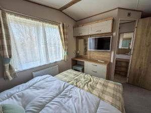 a bedroom with a bed and a tv and window at Luxury Lodge With Stunning Full Sea Views In Suffolk Ref 20234Bs in Hopton on Sea +27 photos