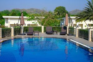 a swimming pool with chairs and umbrellas at ไร่ทิพย์โอชาคีรี ฟาร์มสเตย์ ป่าละอู in Ban Pa Lau