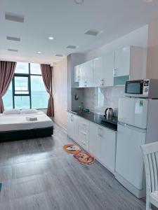 ein Schlafzimmer mit einem Bett und eine Küche mit weißen Schränken in der Unterkunft Pearl Nha Trang Beach Apartment in Nha Trang