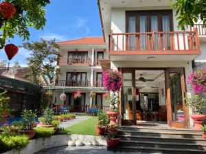 a house with a balcony and a yard with potted plants at Village Moon Villa in Hoi An