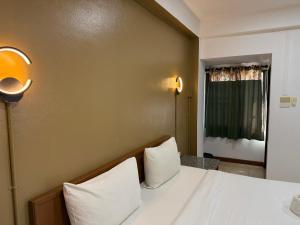 a bedroom with a bed with white sheets and a window at Hua Lin Inn in Chiang Mai