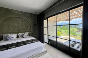 a bedroom with a bed and a large window at Batur Sunsun Kintamani in Kubupenlokan