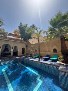 a large swimming pool with chairs and palm trees at Riad Lotus Bleu in Fès
