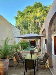 a patio with a table and chairs and an umbrella at Casa Ámbar, tu casa en Mérida in Mérida