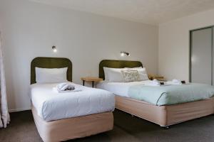 een slaapkamer met twee bedden met witte lakens bij Amber Court Motel Nelson in Nelson