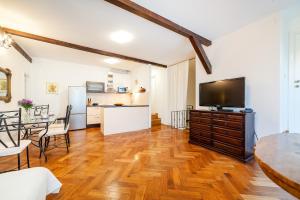 a living room with a large television and a kitchen at Apartment Heart of the City in Šibenik