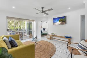 Una sala de estar con un sofá amarillo y una mesa. en 1 Bedroom Apartment at The Queenslander, en Port Douglas