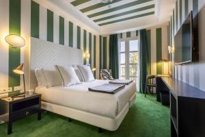 a bedroom with a bed with green and white stripes at Room Mate Collection Valeria, Málaga in Málaga