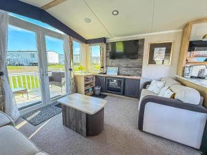 een woonkamer met een bank, een tv en een tafel bij Stunning Caravan With Decking At Haven Hopton-On-Sea Ref 80007L in Great Yarmouth