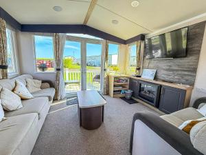 een woonkamer met banken, een tv en een open haard bij Stunning Caravan With Decking At Haven Hopton-On-Sea Ref 80007L in Great Yarmouth