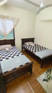 Dos camas en una habitación con ventana. en Cinta Homestay Satu UTHM, en Parit Raja