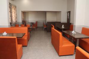 AmarnāthSai Paradise Lodging & Boarding的用餐室配有橙色椅子和桌子