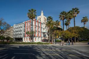 a large white building with palm trees and a street at Room Mate Collection Valeria, Málaga in Málaga