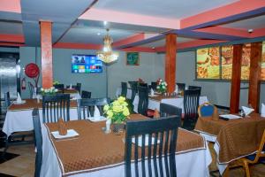 a dining room with tables and chairs and a chandelier at Elanacha Hotel in Arusha