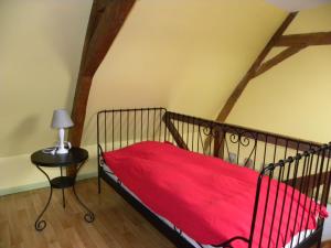 a bedroom with a bed with a red blanket and a table at Entre Caps et Marais in Alembon