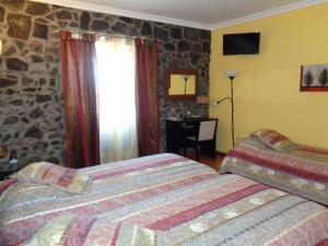 a bedroom with two beds and a stone wall at Casa Das Faias in Santa Cruz da Graciosa