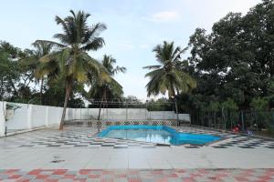 a swimming pool with two palm trees and a fence at Aaditya Greens Near Nelaguli Panchyat Office in Kaglipur