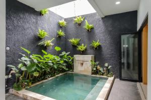 a swimming pool in front of a black wall with plants at INNCA The Amerta Private Villa, Solo in Solo
