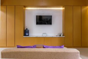 a bed with purple pillows in a room with wooden cabinets at INNCA Amerta Villa, Solo in Solo