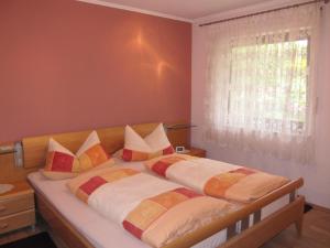 ein Schlafzimmer mit einem Bett mit Kissen und einem Fenster in der Unterkunft Abendstille am Obstgarten mit Terrasse in Zapfendorf