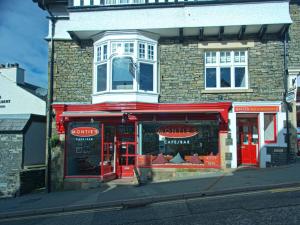 een winkel met rode deuren op een bakstenen gebouw bij Monties Guest House - Adults ONLY in Bowness-on-Windermere
