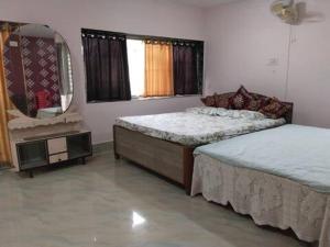 a bedroom with two beds and a mirror in it at Shobuj Kutir সবুজ কুটির in Ghātsīla