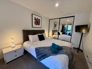 堪培拉Midnight Luxe 1BR 1Bath Apartment 104 in the heart of Braddon Pool Sauna Secure Parking Wine WiFi的有两张床和一面镜子的卧室