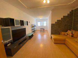 ein Wohnzimmer mit Fernseher, Sofa und Treppe in der Unterkunft EstrellaMar in Arinaga