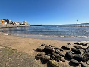 ein Strand mit Felsen im Sand und Wasser in der Unterkunft EstrellaMar in Arinaga