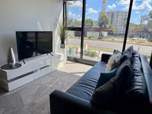 堪培拉Midnight Luxe 1BR 1Bath Apartment 104 in the heart of Braddon Pool Sauna Secure Parking Wine WiFi的配有沙发和平板电视的客厅