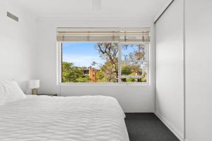 Un dormitorio con una cama blanca y una ventana. en The Sunlit Fern - Minutes from Dining & Coastline, en Sídney 7 fotos más