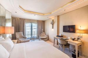 a hotel room with a bed and a desk and a television at Wyndham Grand Istanbul Kalamış Marina Hotel in Istanbul