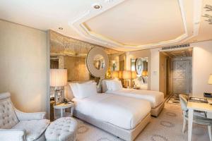 a bedroom with two beds and a chair and a desk at Wyndham Grand Istanbul Kalamış Marina Hotel in Istanbul