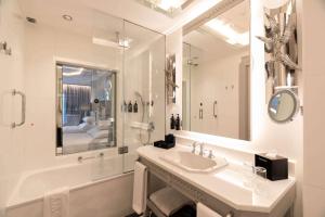 a white bathroom with a sink and a shower at Wyndham Grand Istanbul Kalamış Marina Hotel in Istanbul